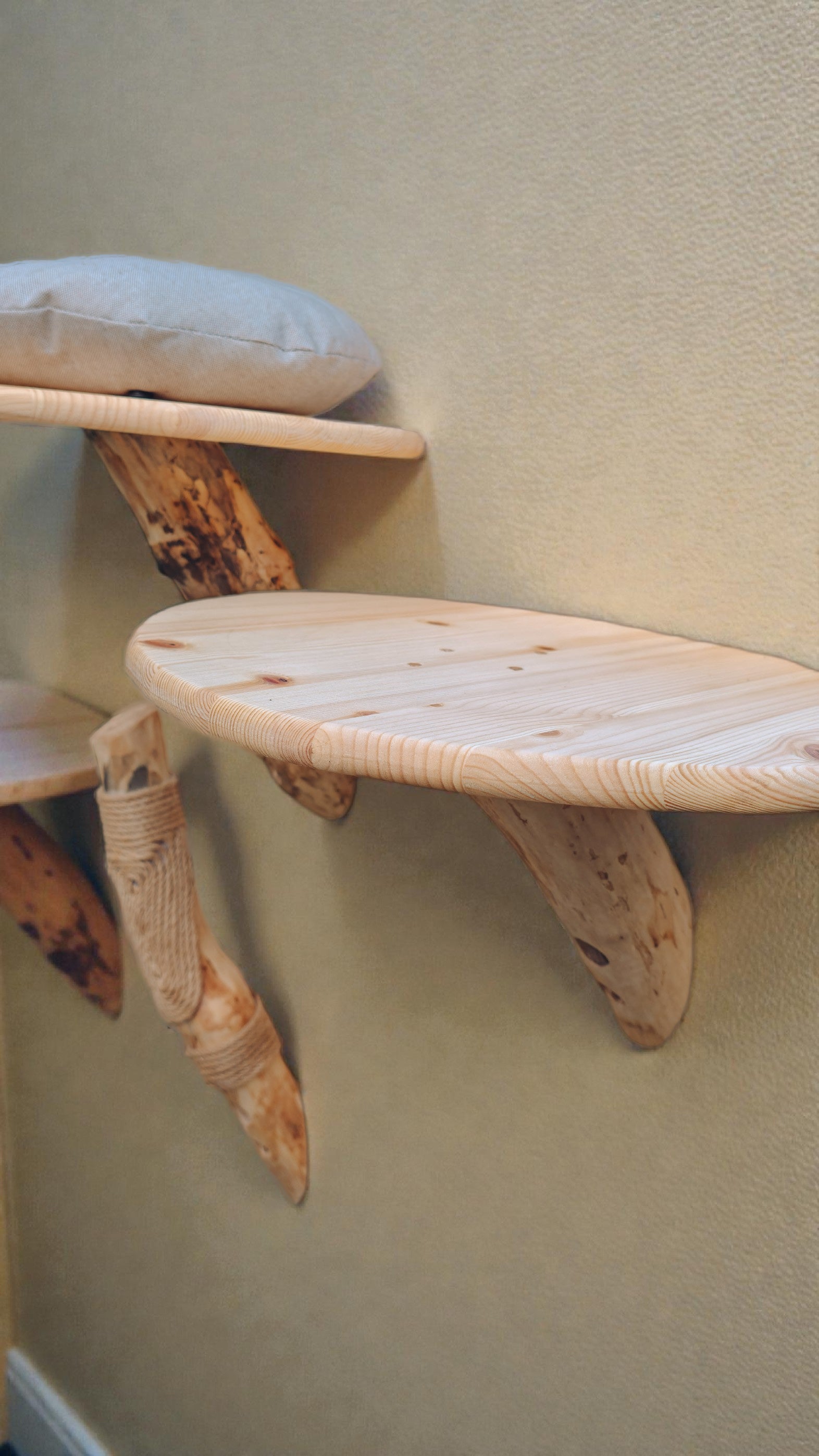 Wooden cat shelf with a cushion on a beige wall