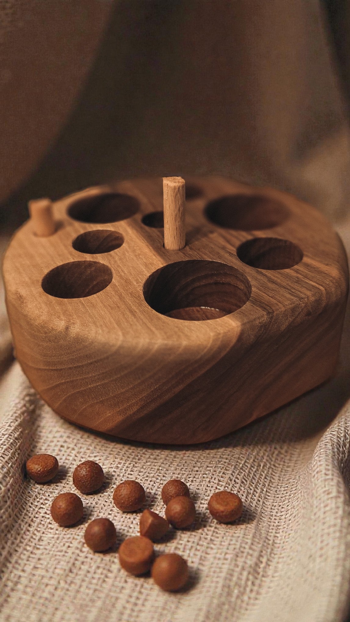 Walnut wooden cat feeding puzzle with linen background and cat kibble 